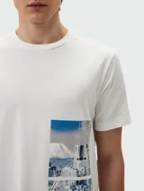 Camiseta blanca de manga corta marca BOSS, con estampado rectangular vertical en el lateral izquierdo que incluye una fotografía de paisaje urbano en tonos azules y grises.