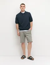 Bermuda chino de corte recto, color verde militar, confeccionada en algodón con elastano. Cuenta con bolsillos laterales de estilo italiano y bolsillos traseros con botón.