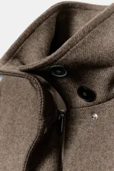 Abrigo corto de paño con mezcla de lana, color marrón topo. Presenta cuello subido, manga larga, cierre frontal con cremallera y botones a presión ocultos, y dos bolsillos de plastrón en el delantero.