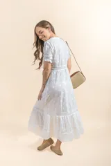 Vestido midi blanco con bordado floral, escote en V con botones, mangas cortas abullonadas con lazos y falda con volantes.