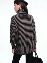 Polera de tejido de punto con diseño de rayas horizontales en tonos marrón y negro, cuello alto, mangas largas con hombros caídos y corte holgado.