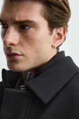 Cazadora de corte regular fit en color negro. Presenta cuello solapa con un cuello interior de punto desmontable mediante cremallera. Cuenta con cierre frontal de cremallera oculta por una solapa con botones a presión, bolsillos de plastrón con solapa en la cadera y mangas largas con puños abotonados.