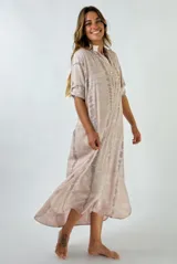 Vestido largo color nude con estampado de líneas verticales difuminadas en gris. Tiene cuello mao, mangas cortas con presilla y cierre parcial con botones.