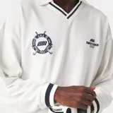 Buzo tipo polo de manga larga en color marfil, confeccionado en suave algodón piqué con detalles en azul marino en el cuello y los puños. Presenta escudos bordados en el pecho y puños elásticos.