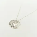 Collar plateado con dije circular calado de diseño abstracto.