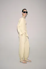 Pantalón bombacho de tiro medio, confeccionado en hilatura con mezcla de viscosa, con estampado de rayas verticales en tonos beige y amarillo claro, cintura elástica ajustable con cordón y puños en los tobillos.