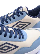 Championes Umbro modelo Volcan, con diseño urbano en combinación de colores beige y azul. Presentan el logo de la marca en el lateral, suela blanca de plataforma y cierre con cordones.