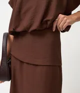 Pollera midi de viscosa color marrón, con diseño de canesú estructurado en la cintura que aporta una división visual y un ajuste definido.