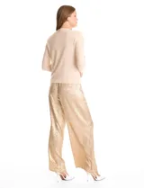 Buzo de tejido fino color beige, con cuello redondo decorado con apliques de brillos y mangas largas.