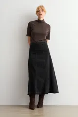 Falda larga de jean color negro, con diseño de paneles verticales y ruedo deshilachado.