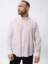 Camisa de manga larga con estampado de microcuadros en tonos azul y blanco. Presenta cuello clásico con botones, cierre frontal abotonado y detalle de logo bordado en el pecho.