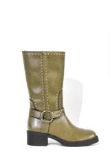 Bota de caña media color marrón con detalle de tachas plateadas en el borde superior y en la correa con hebilla que rodea el tobillo. Tiene taco bajo y punta redondeada.