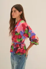 Kimono de corte holgado con estampado floral abstracto en tonos fucsia, rosa, verde y azul. Presenta mangas tres cuartos y diseño abierto frontal.