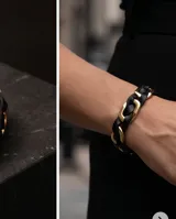 Pulsera de diseño trenzado que combina tiras de cuero negro con eslabones de acero en tono dorado. Cuenta con un cierre magnético integrado.