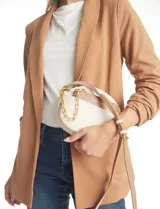 Cartera tipo bandolera de eco cuero con silueta de media luna, color beige y detalles en marrón claro. Incluye un monedero/tarjetero independiente en el bolsillo frontal y una cadena decorativa de eslabones dorados.
