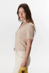 Remera lisa de color beige, con escote en V y mangas cortas de corte clásico.