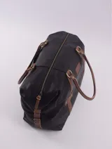 Bolso de viaje tipo duffle, confeccionado en cuero natural color azul con textura, con detalles de correas y asas en cuero color suela. Cuenta con cierre superior, bolsillo interior con cierre y compartimento para celular.