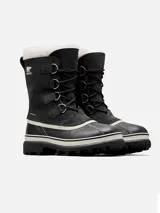 Botas de nieve Sorel modelo Caribou para mujer, de color negro con base de goma vulcanizada impermeable y detalles en blanco. Cuentan con parte superior de gamuza y nylon, cordones frontales con anillas metálicas y borde superior de pelo sintético blanco.
