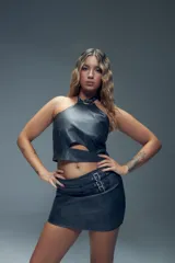 Minifalda gris de símil cuero con apliques de tres tiras con hebillas metálicas y cierre invisible atrás.