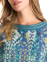 Blusa de calce relajado con estampado geométrico multicolor en tonos azules, verdes y amarillos. Presenta escote redondo con detalle tejido en el contorno, mangas tres cuartos y silueta levemente evasé.