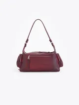 Cartera de hombro confeccionada en cuero vacuno color bordó con acabado desgastado. Presenta múltiples bolsillos exteriores con cierre en el frente, dorso y laterales, herrajes metálicos plateados y logo de la marca aplicado en el frente.