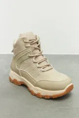 Zapatilla tipo hiking de caña media, confeccionada en una combinación de símil cuero y nylon en tonos beige y rosa suave. Presenta cordones al tono, interior acolchado para mayor abrigo y suela de goma dentada en color marrón con entresuela gris.