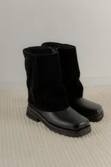 Bota de caña media combinada en cuero vacuno y gamuza, con diseño de solapa superior y punta cuadrada. Cuenta con suela de goma plana y tacón bajo.