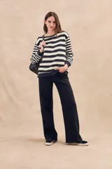 Sweater de punto a rayas horizontales anchas en color negro y crudo, de corte oversize, mangas largas y cuello redondo.