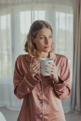 Pijama de satén elastizado color celeste, compuesto por una camisa de manga larga con cuello solapa, botones frontales y bolsillo en el pecho, y un pantalón recto con cintura elástica y lazo ajustable.