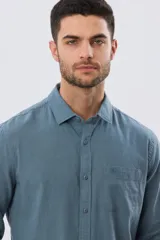 Camisa de lino de manga larga en color beige, con cuello camisero, cierre frontal de botones y un bolsillo ojal en el pecho.