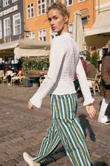 Top de manga larga con textura nido de abeja, escote en pico con detalle de volantes y cierre frontal mediante lazos ajustables.