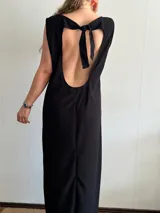 Vestido largo negro de tejido texturizado, sin mangas y con escote bote. Presenta dos tajos laterales altos.