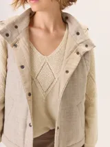 Chaleco con capucha, presenta una espalda de pelo sintético en color marrón oscuro con etiqueta de cuero negra y una capucha de tela tipo denim azul. Diseño original con mezcla de texturas.