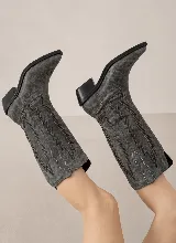 Bota de estilo texano confeccionada en cuero genuino, con caña alta y diseño de costuras decorativas en contraste. Presenta punta fina y taco cuadrado de madera.
