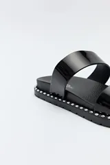 Sandalias planas plateadas con dos tiras anchas y suela negra con detalles metálicos.