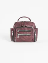 Mochila bandolera de cuero sintético en color bordó con efecto desgastado. Presenta múltiples compartimentos con cierre metálico, incluyendo dos bolsillos frontales y dos laterales. Incluye manija superior y correas ajustables.