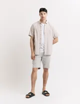 Bermuda de gabardina en color verde medio, con corte recto, bolsillos laterales y cierre frontal con botón.