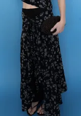 Falda midi cruzada color negro con estampado floral en tono gris, con sistema de atado en la cintura.