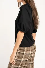 Remera de algodón negro con mangas cortas abullonadas, cuello redondo y costura central frontal.