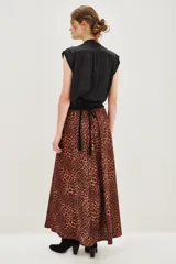Falda larga de corte acampanado con estampado animal print de leopardo en tonos caramelo y negro. Presenta una cintura alta con detalle de banda decorativa con tachas metálicas.