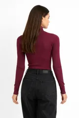 Polera negra de ajuste al cuerpo, con cuello alto y mangas largas, confeccionada en tejido de poliéster.