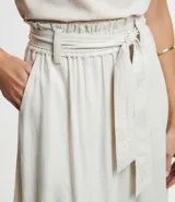 Pollera midi de corte clochard confeccionada en mezcla de viscosa y lino. Presenta cintura elástica con lazo ajustable del mismo tejido, bolsillos laterales y una caída fluida.