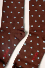 Medias largas color marrón con estampado de lunares celestes. Tienen un corazón rojo bordado con la letra 'R' en blanco en la parte superior y la palabra 'Rotunda' en rojo en el lateral del pie.