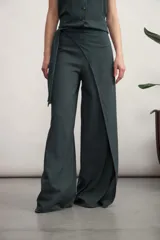 Pantalón ancho de tiro alto, color verde oscuro, con diseño envolvente tipo pareo o wrap-around, asegurado con un lazo en la cintura.