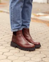 Botinetas de cuero color chocolate con diseño de paneles combinados en cuero liso y cuero texturizado. Presentan una suela track gruesa de goma negra y un corte tipo chelsea.