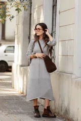Vestido midi de tejido de punto color gris, con cuello a la base, mangas tres cuartos tipo oxford y detalle de calado geométrico en las mangas y en el ruedo.