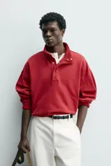 Sudadera de corte relajado color rojo con efecto lavado. Presenta cuello subido con cierre frontal de botones a presión, manga larga y puños y ruedo terminados en rib.