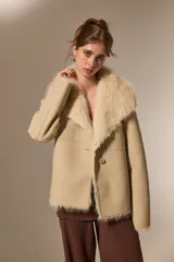 Chaqueta de eco-cuero color beige con interior y cuello de piel sintética al tono. Presenta un diseño holgado, cierre frontal con un botón y solapas amplias.