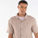 Camisa de manga corta de punto jacquard color beige, con cuello camisero y cierre frontal de botones.