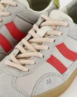 Championes de estilo retro con capellada de gamuza en tono gris claro, detalles laterales en rojo y refuerzo en el talón color verde lima. Presenta suela de goma color caramelo y cierre mediante cordones.